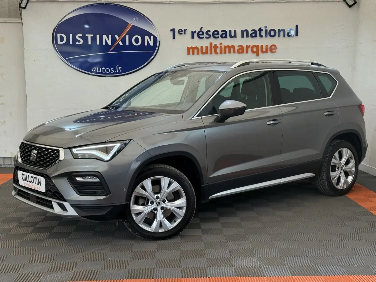 SEAT Ateca gris clair vue de profil côté gauche, avec jantes alliage et barres de toit chromées visibles.