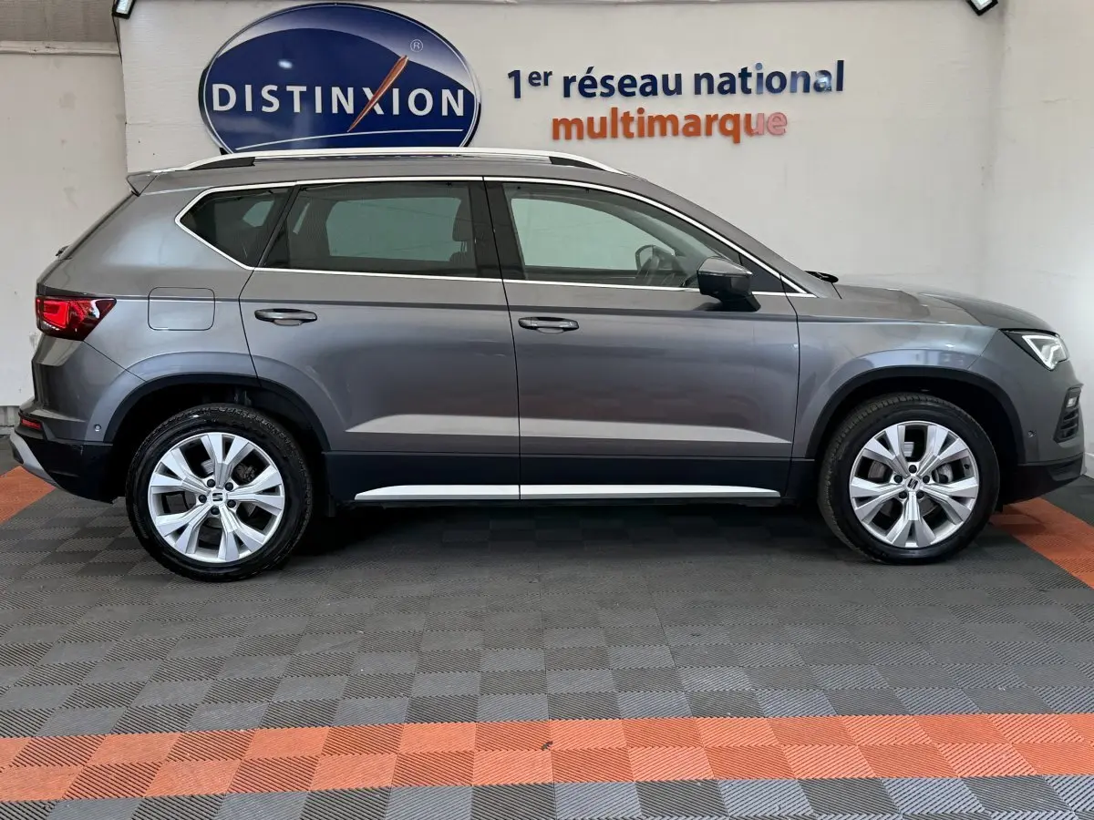 Profil droit d'un SEAT Ateca gris clair 2023, SUV compact avec jantes alliage et barres de toit chromées visibles.