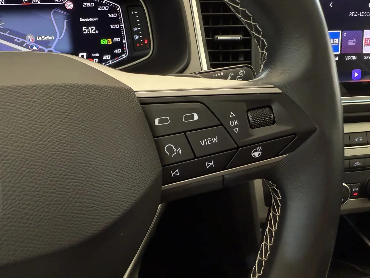 Gros plan sur le volant noir avec commandes multifonctions et affichage numérique du tableau de bord du SEAT Ateca 2023.