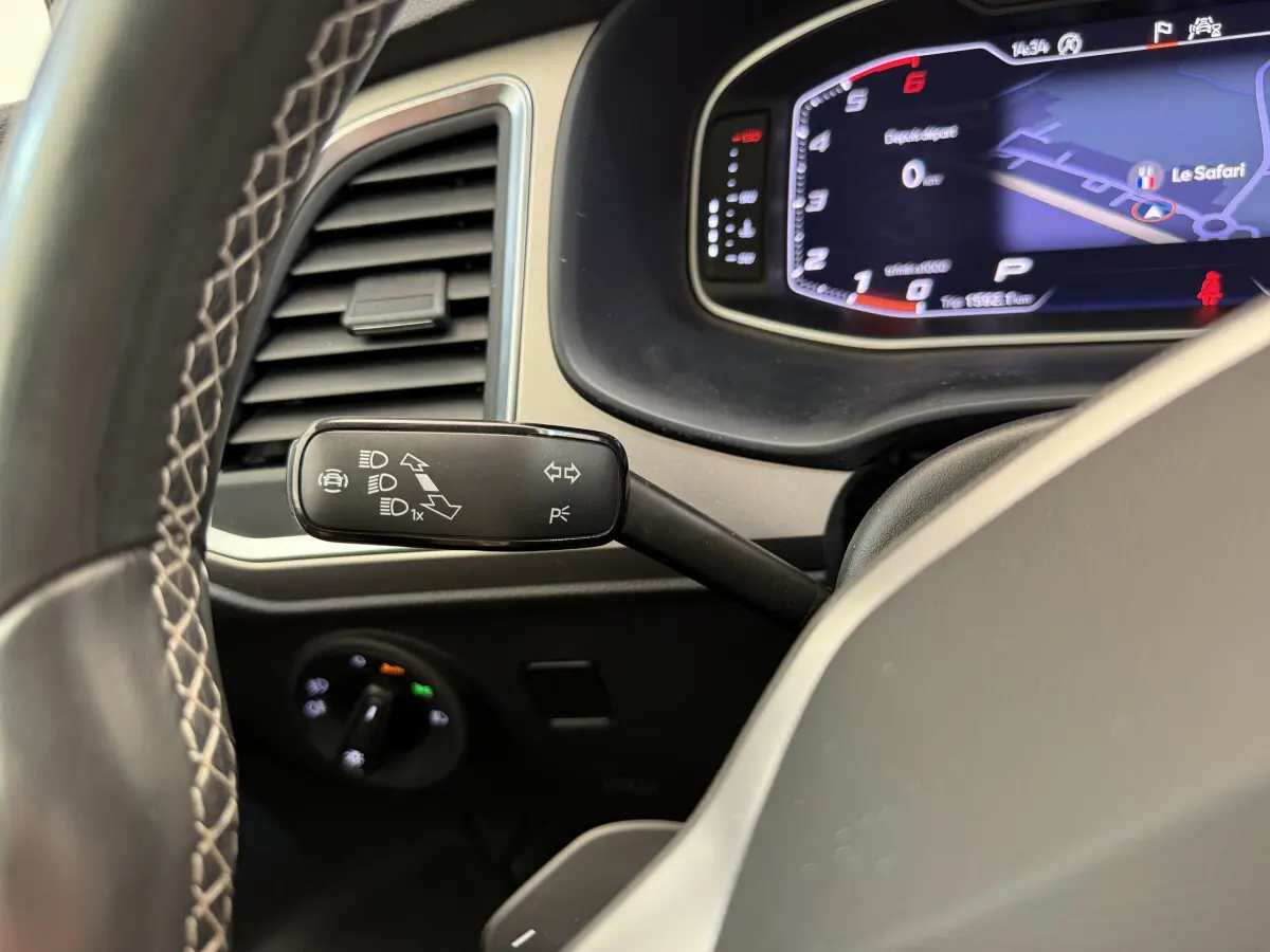 Gros plan sur la manette de clignotant à gauche du volant dans le tableau de bord numérique du SEAT Ateca gris clair 2023.