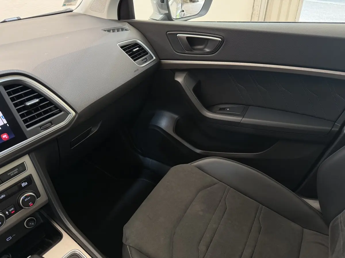 Vue intérieure côté passager du SEAT Ateca 2023, montrant siège en tissu gris et tableau de bord noir avec écran tactile.