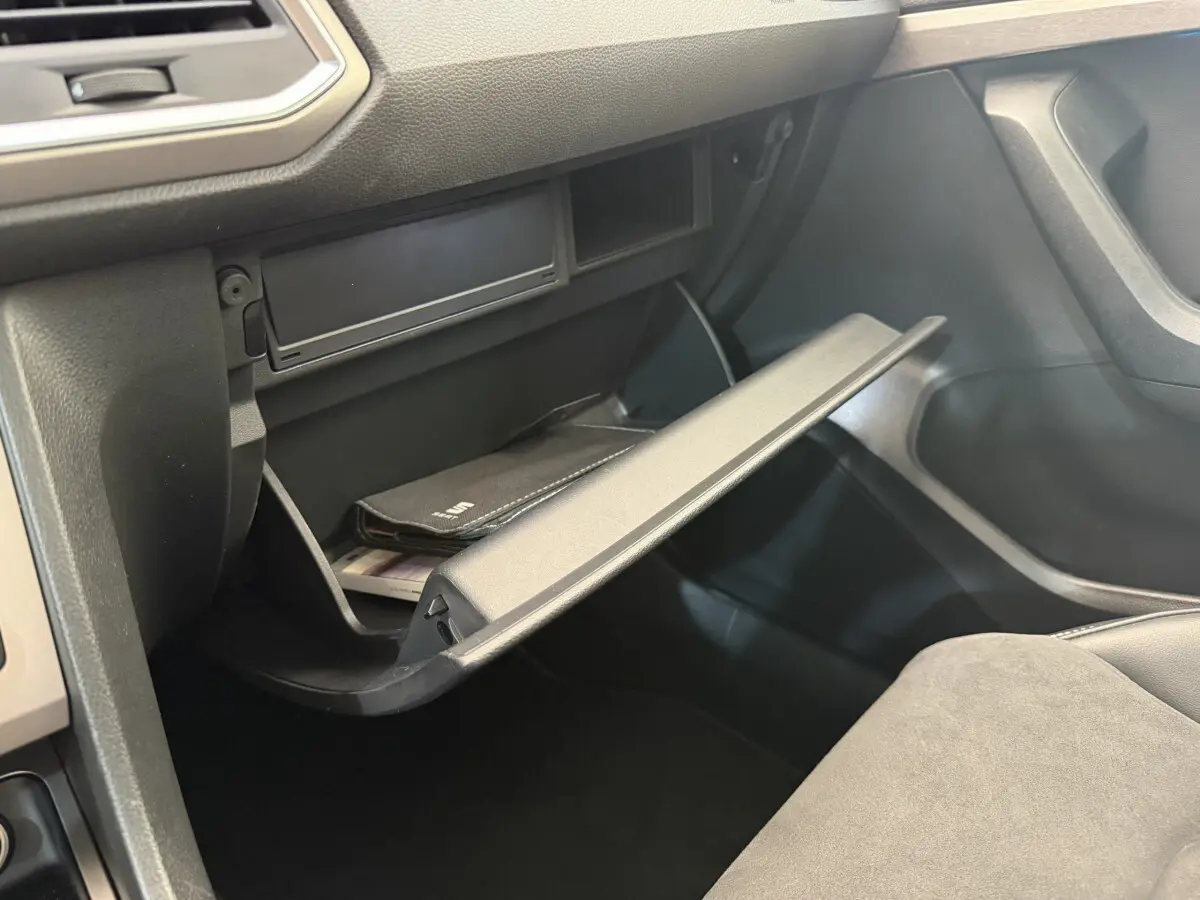 Gros plan de la boîte à gants ouverte côté passager dans l'habitacle noir du SEAT Ateca gris clair 2023.