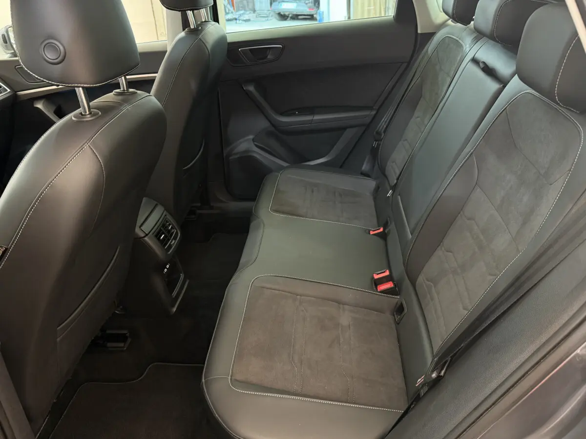 Vue intérieure côté droit des sièges arrière en cuir noir du SEAT Ateca gris clair 2023 avec surpiqûres blanches.