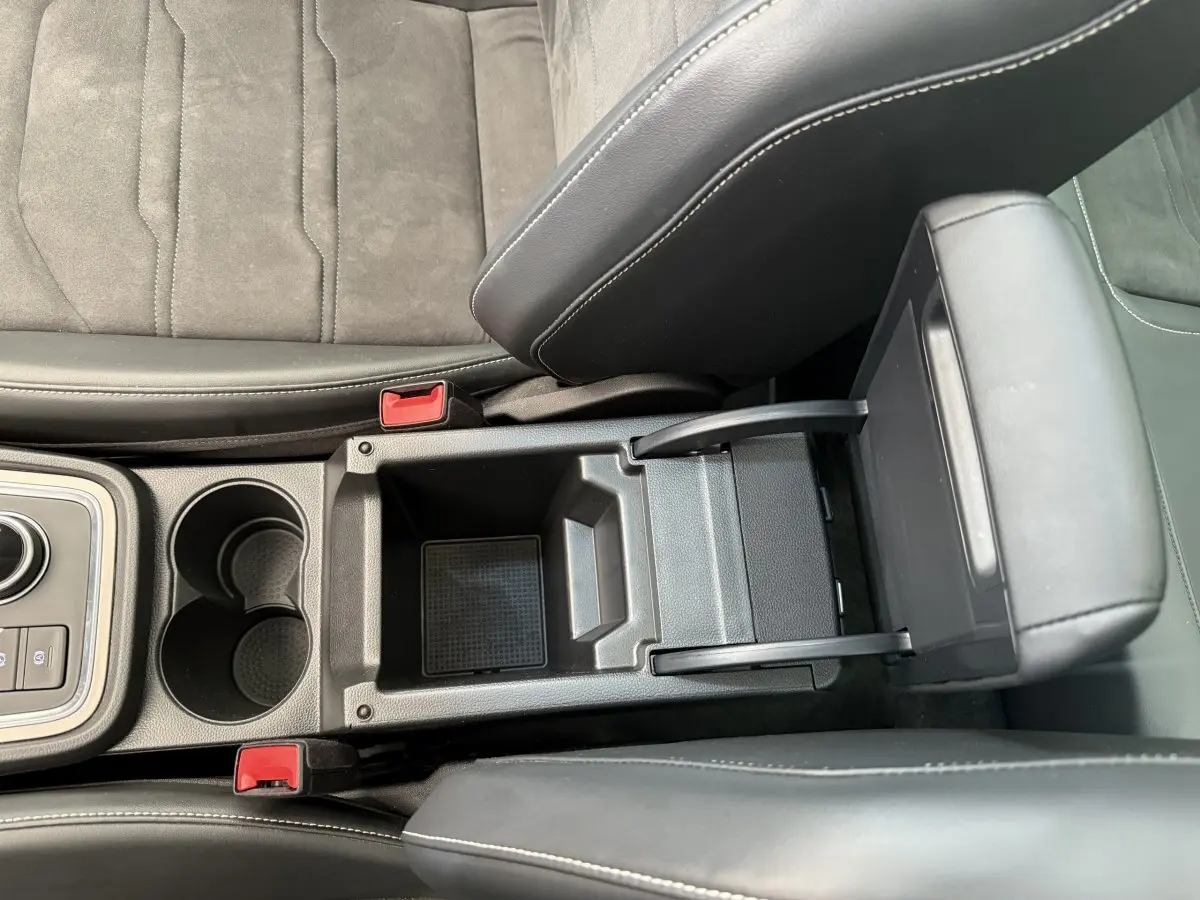 Gros plan sur la console centrale noire avec accoudoir relevé et porte-gobelets du SEAT Ateca gris clair 2023.