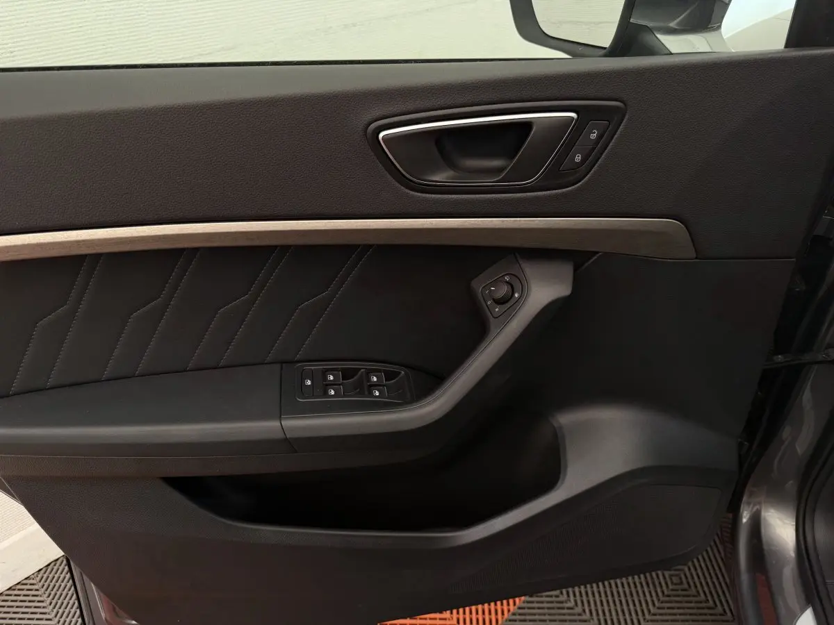 Gros plan sur la porte avant gauche noire avec insert bois clair et commandes électriques de la SEAT Ateca 2023.