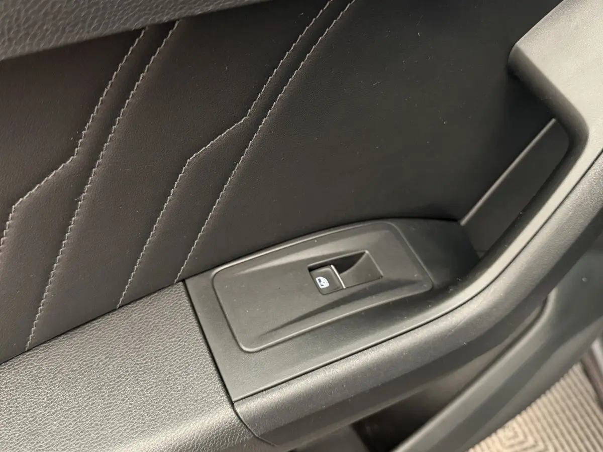 Gros plan sur le bouton de verrouillage des vitres sur la porte intérieure noire du SEAT Ateca gris clair 2023