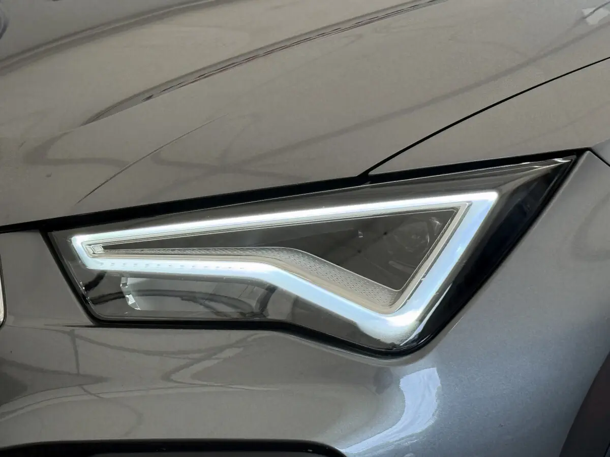 Gros plan sur le phare avant droit LED du SEAT Ateca gris clair 2023 avec contour lumineux distinctif en forme de flèche.
