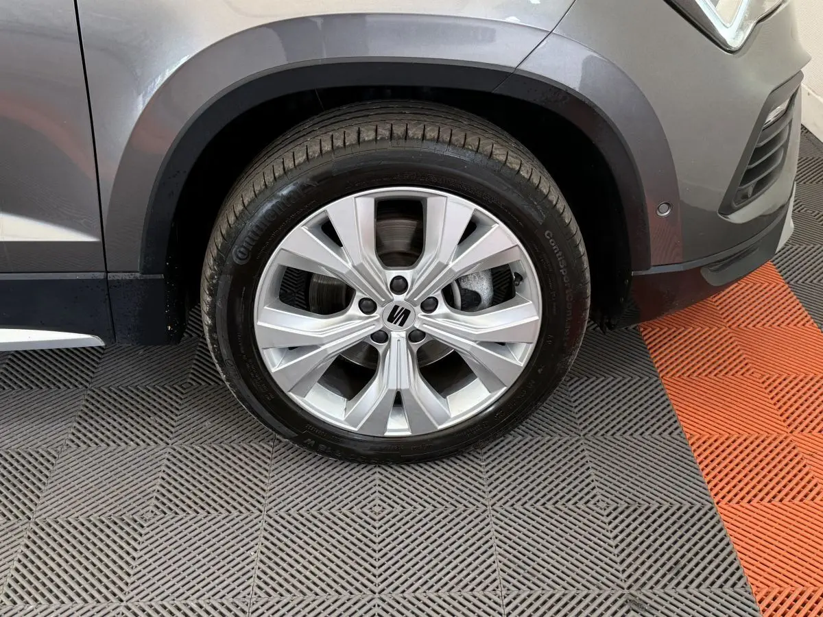 Gros plan sur la roue avant droite gris clair du SEAT Ateca 2023 avec jante alu et logo central visible.