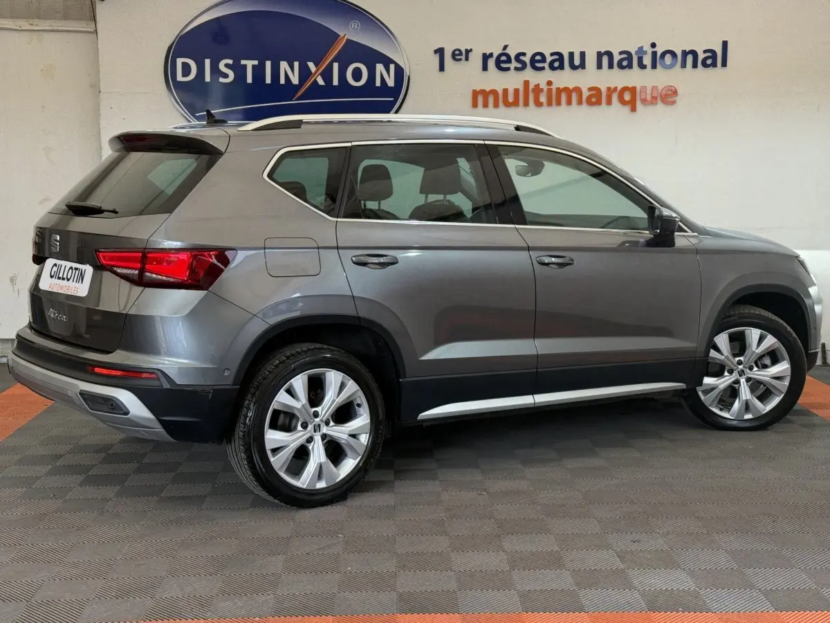 Vue latérale droite d'un SEAT Ateca gris clair 2023 garé en intérieur avec jantes alliage et toit ouvrant.