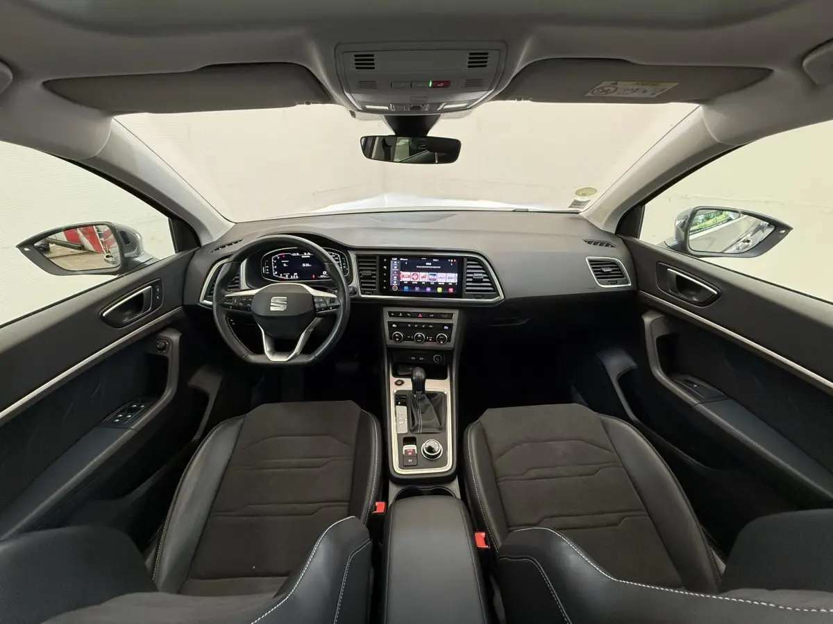 Vue intérieure avant du SEAT Ateca 2023 avec tableau de bord noir, écran tactile central et volant multifonctions.