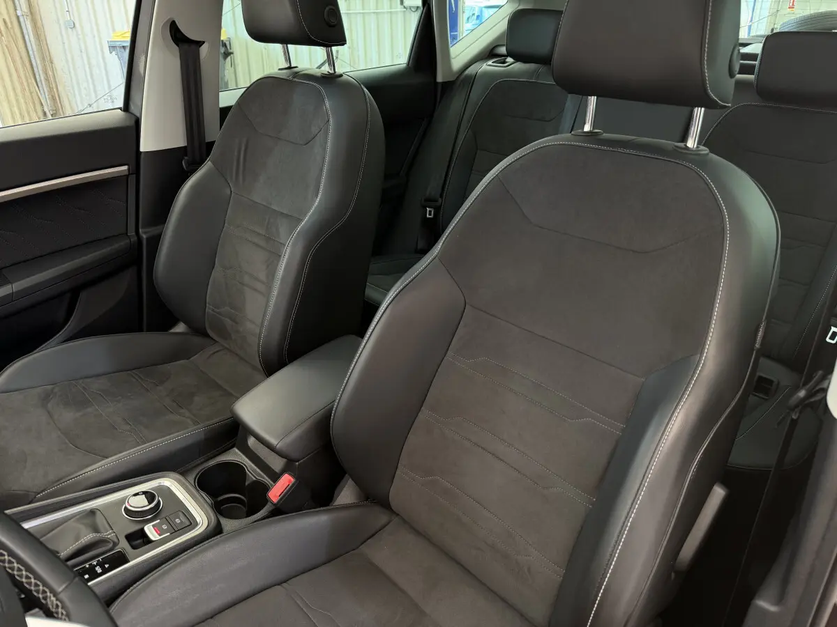 Intérieur du SEAT Ateca 2023, vue sur sièges avant en cuir noir avec surpiqûres blanches et console centrale.