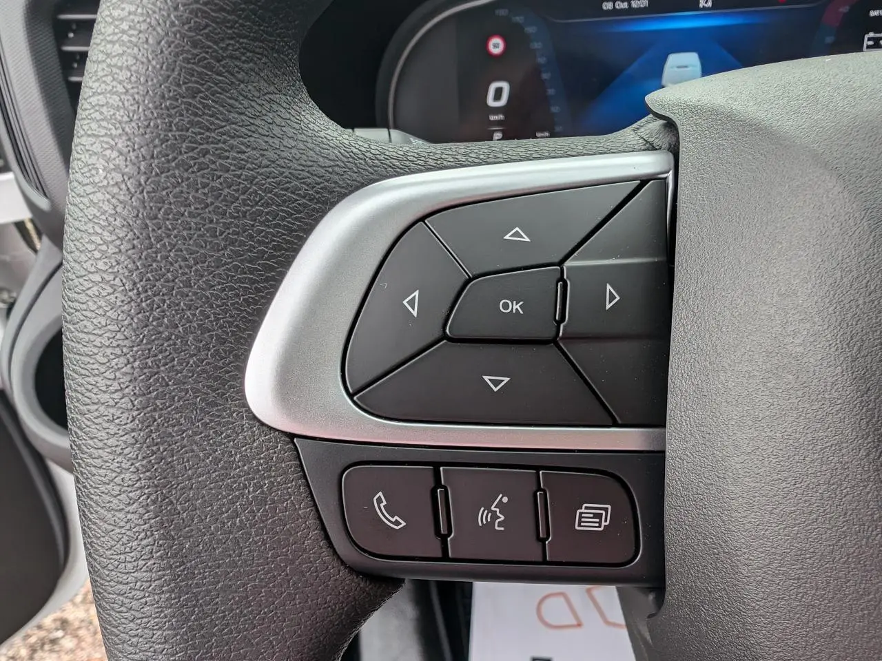 Gros plan sur les commandes multifonctions du volant du Iveco Daily blanc, avec boutons directionnels et appels.