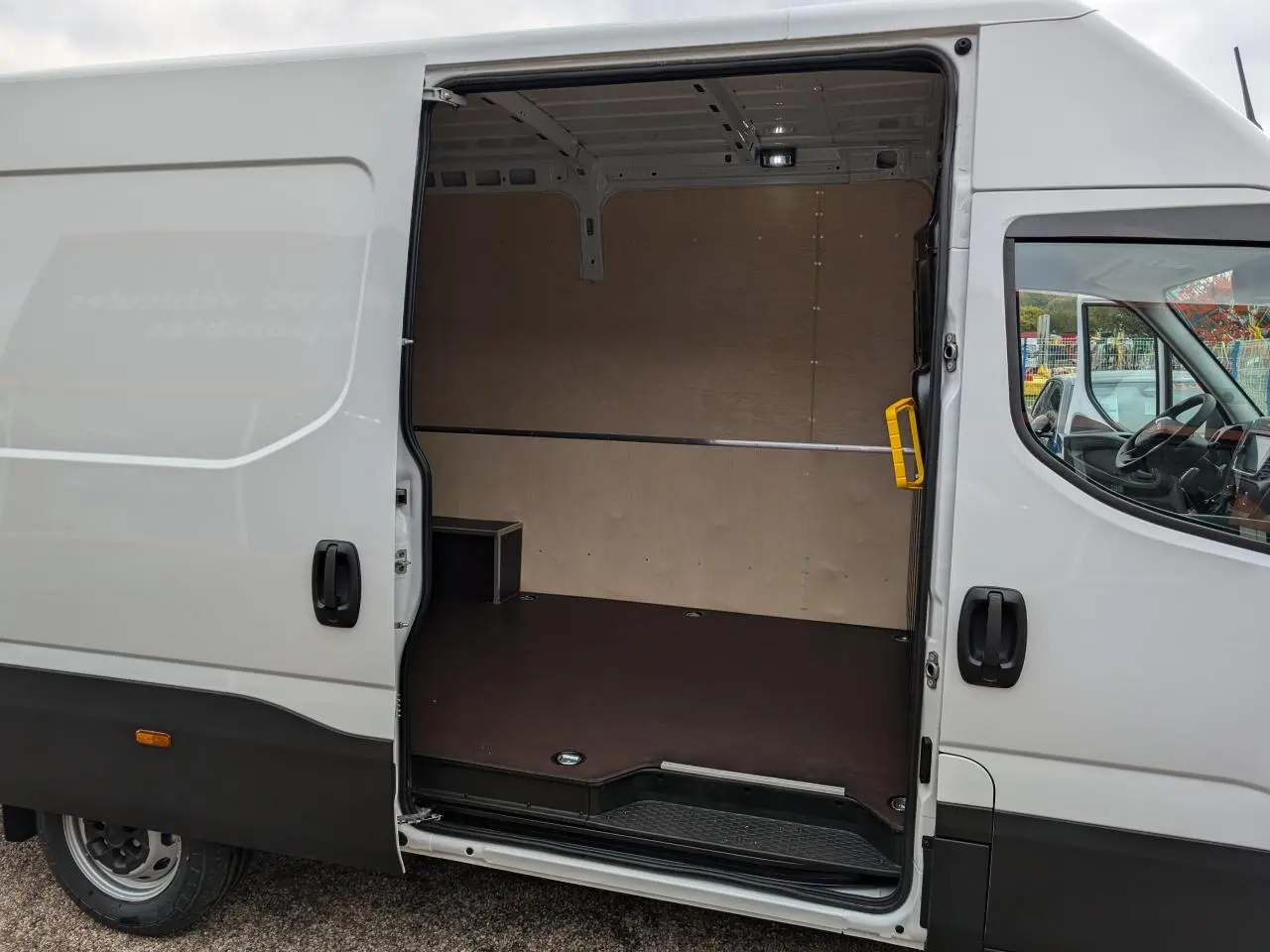 Vue latérale droite d'un Iveco Daily blanc 2025 avec porte coulissante ouverte dévoilant l'espace de chargement vide.