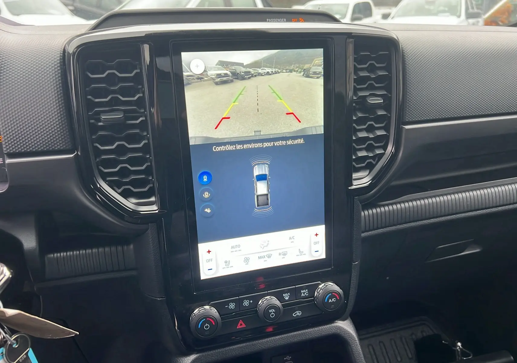 Vue rapprochée de l’écran central tactile du Ford Ranger 2025 gris carbone, affichant la caméra de recul et les commandes climatisation.