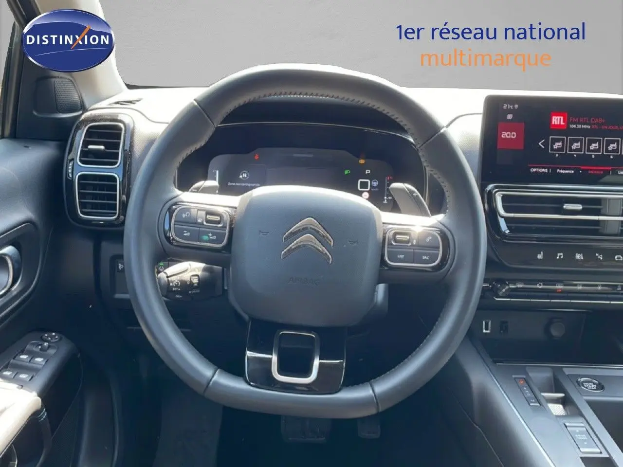 Vue intérieure centrée sur le volant cuir noir du Citroën C5 Aircross 2025 avec tableau de bord digital et écran tactile.