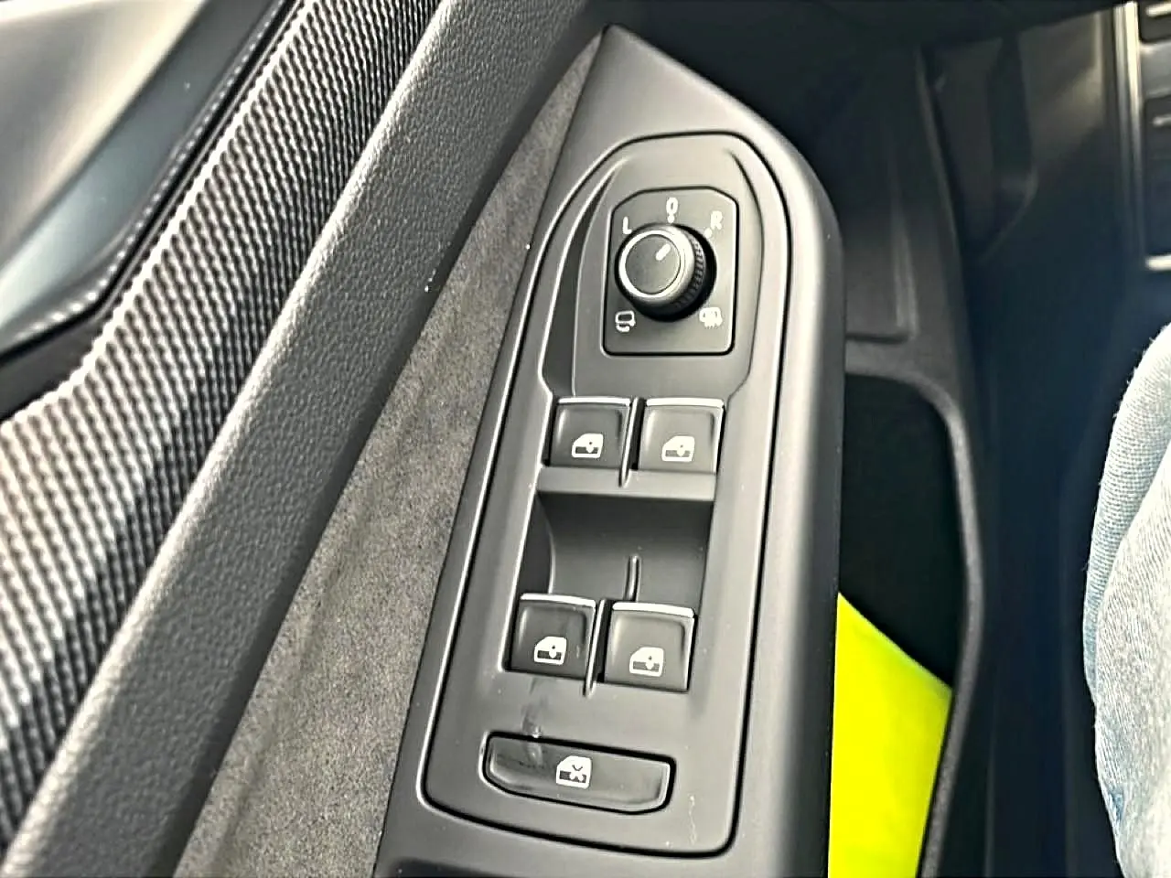 Vue rapprochée des commandes de lève-vitres et réglage des rétroviseurs côté conducteur d'une Volkswagen Golf noire 2026.