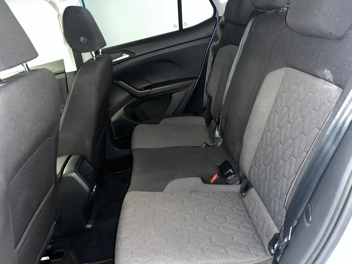 Vue latérale intérieure montrant la banquette arrière en tissu gris du Volkswagen T-Cross 2024 avec vitres surteintées.