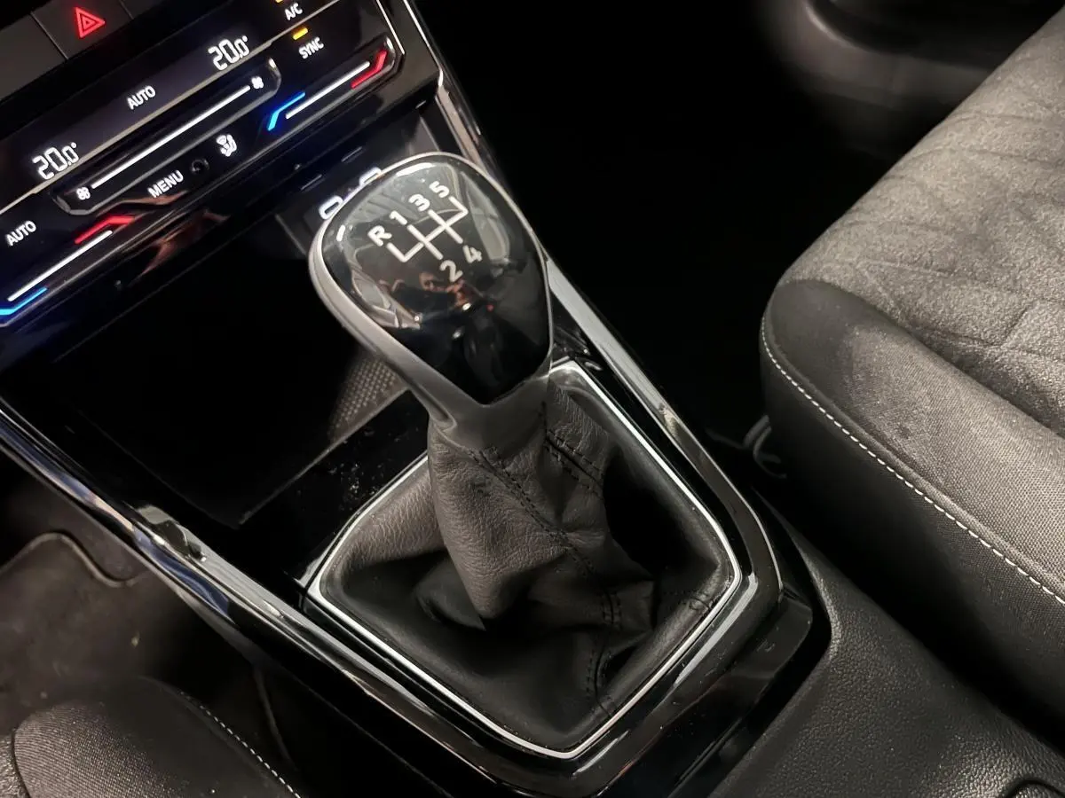 Le levier de vitesses manuel en cuir noir du Volkswagen T-Cross 2024, avec console centrale et siège tissu gris.