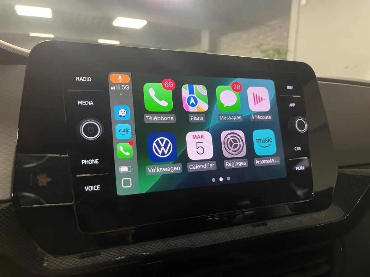 Écran tactile central du Volkswagen T-Cross 2024 affichant l'interface Apple CarPlay colorée en intérieur noir.