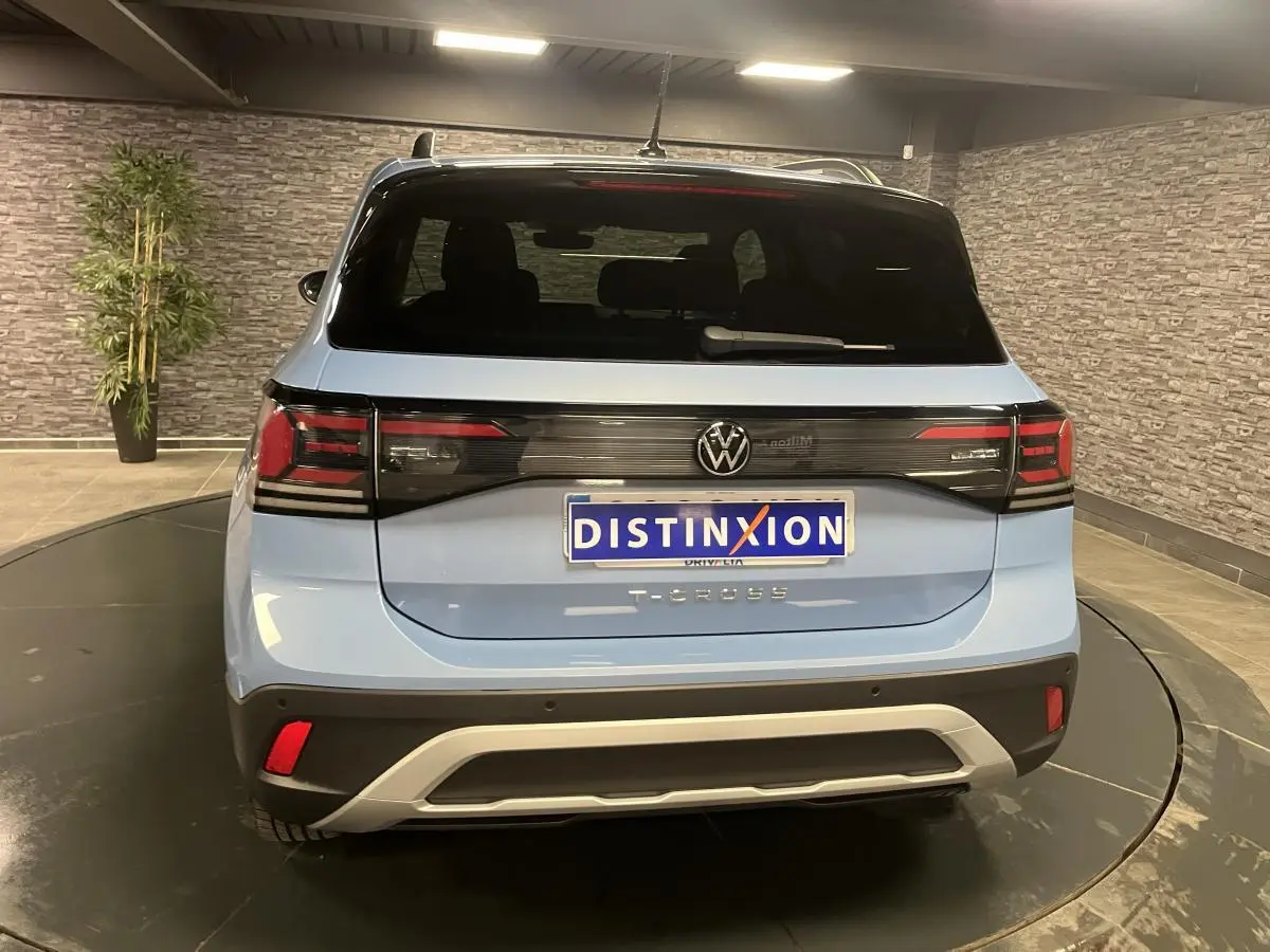 Vue arrière d'un Volkswagen T-Cross bleu clair 2024 avec feux arrière LED et lunette arrière surteintée.