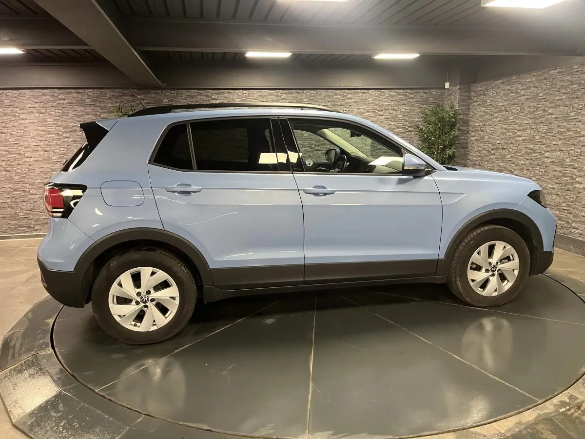 Profil côté gauche d'un Volkswagen T-Cross bleu clair 2024, avec vitres arrière surteintées et jantes alliage argent.