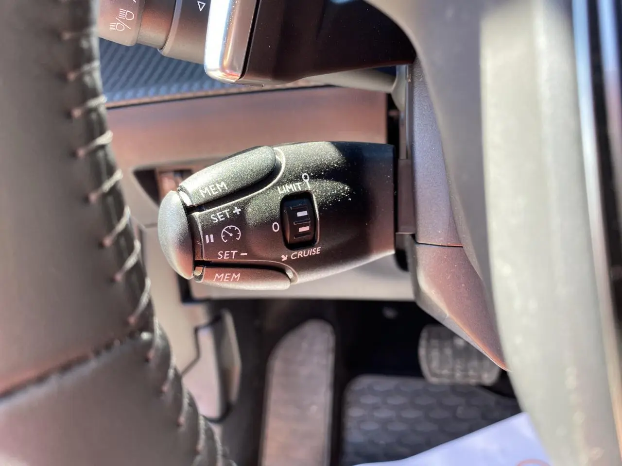 Gros plan sur la commande de régulateur de vitesse à gauche du volant du Peugeot 2008 bleu 2021 Active Pack.