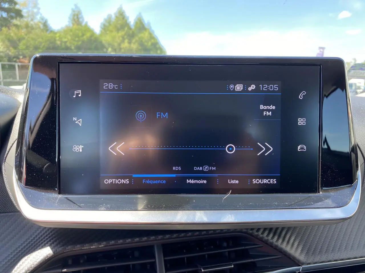 Écran tactile central du tableau de bord du Peugeot 2008 2021 affichant la radio FM en extérieur lumineux