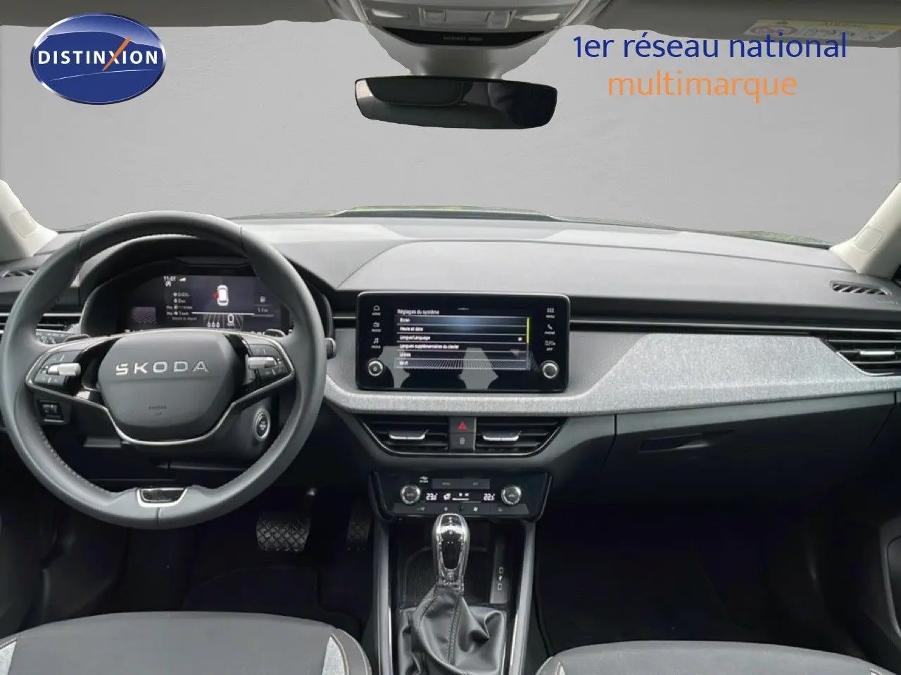Vue intérieure frontale du tableau de bord gris et noir du Skoda Kamiq 2025 avec écran tactile et volant multifonction.