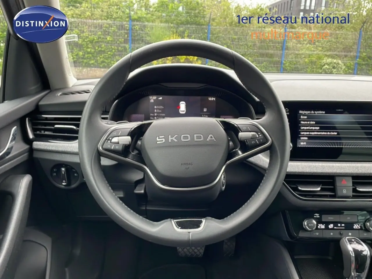 Vue intérieure centrée sur le volant SKODA noir, avec tableau de bord digital et écran tactile du KAMIQ 2025.