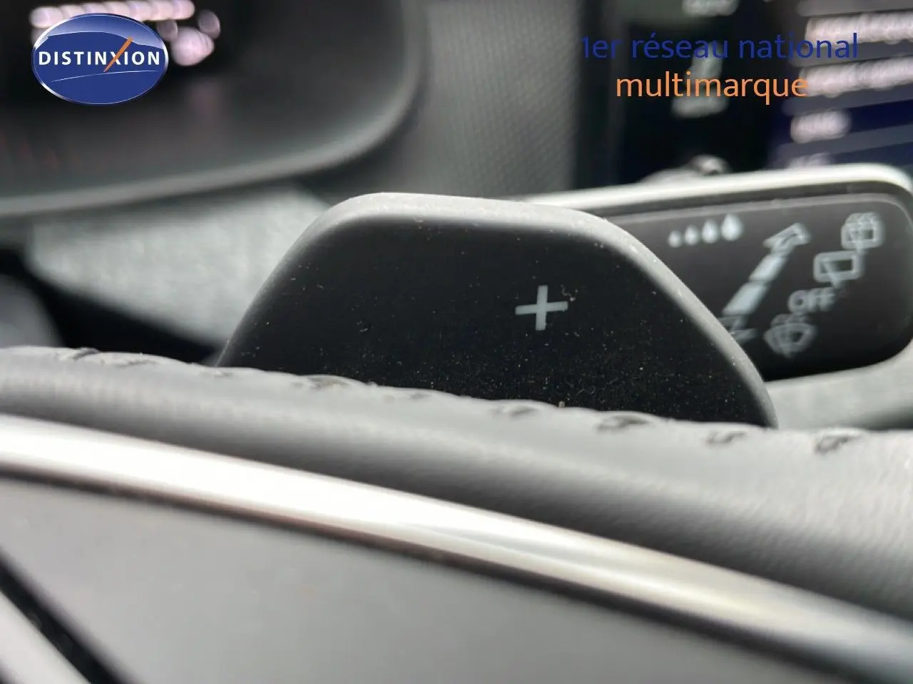 Gros plan sur la palette de changement de vitesse "+" derrière le volant en cuir noir du Skoda Kamiq gris graphite.