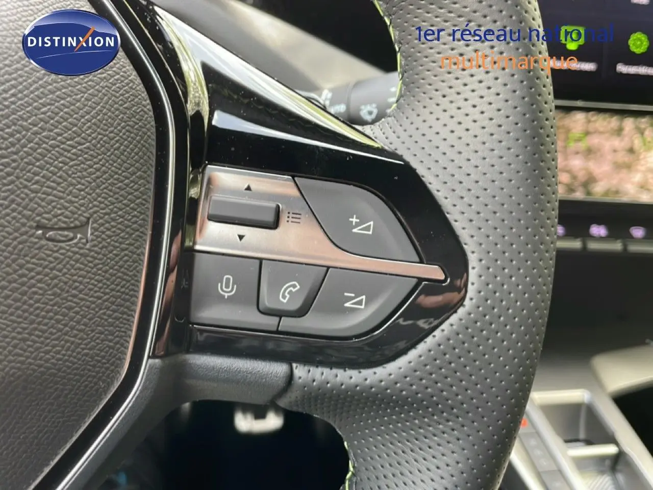 Gros plan sur le volant perforé de la Peugeot 308 gris Artense, avec commandes intégrées visibles côté gauche.