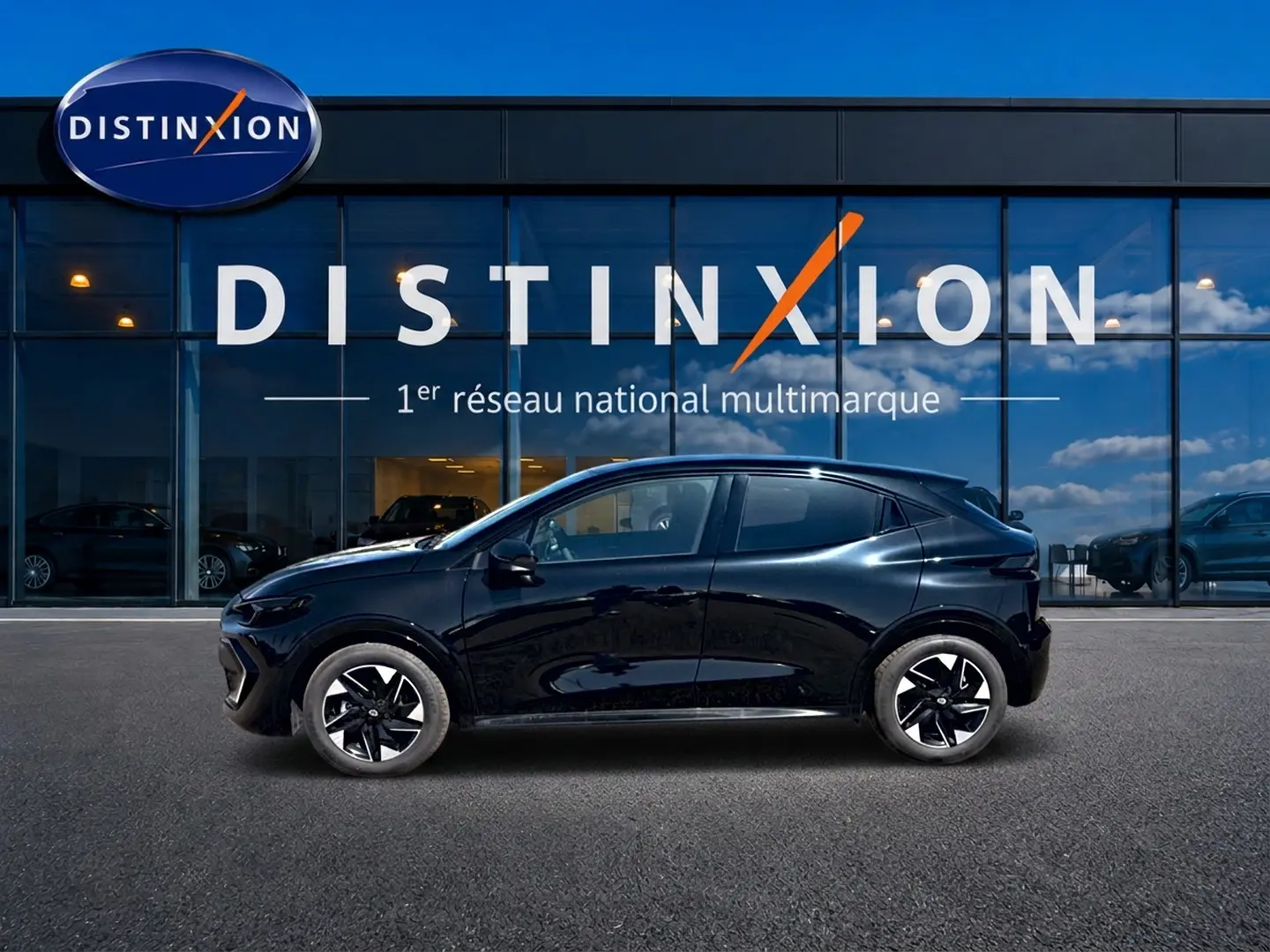 Profil droit de la Renault Clio VI noire 2026, avec jantes alliage et lignes fluides devant une vitrine Distinxion.