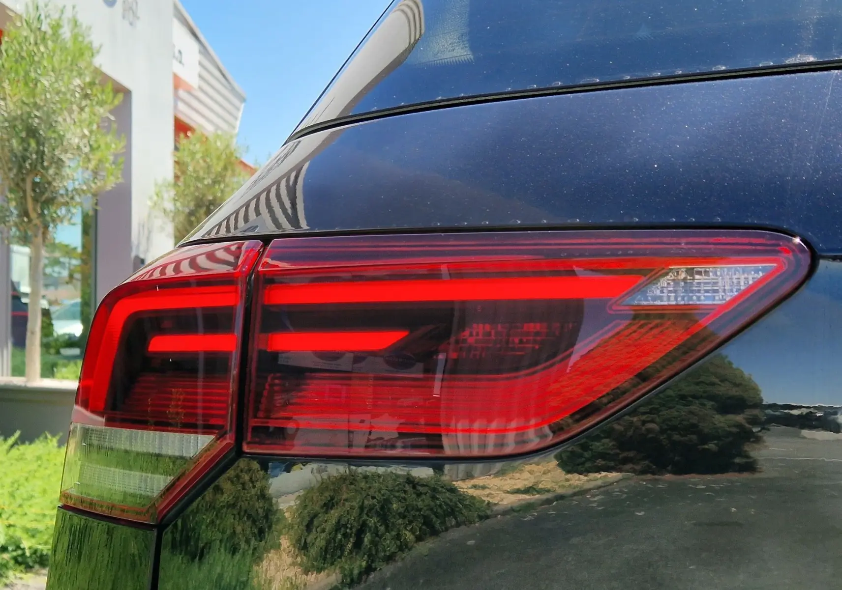 Gros plan sur le feu arrière droit d'une Volkswagen Golf VIII noire métallisée, soulignant ses lignes LED modernes.