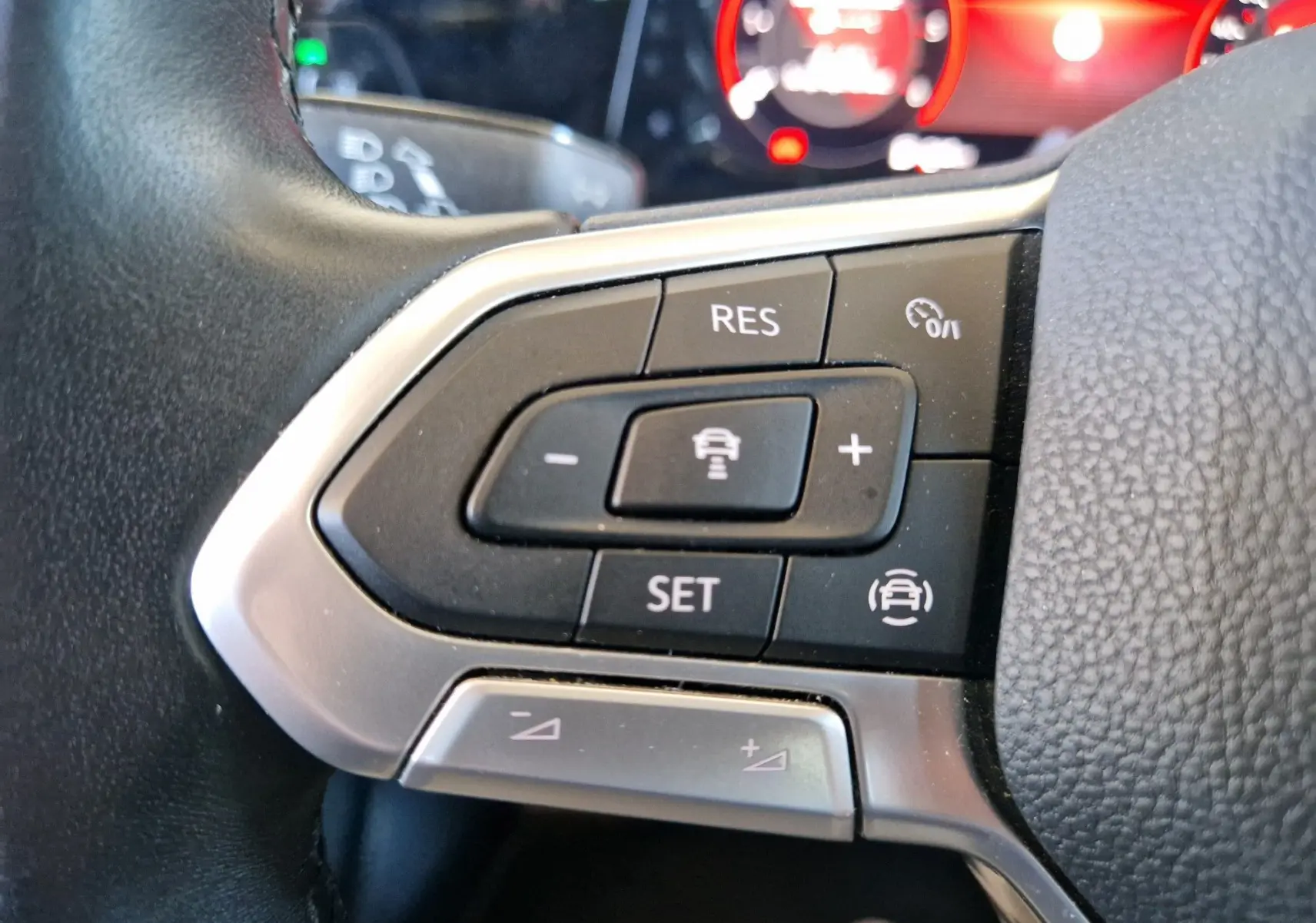 Gros plan sur les commandes de régulateur de vitesse au volant d'une Volkswagen Golf VIII noire de 2021.