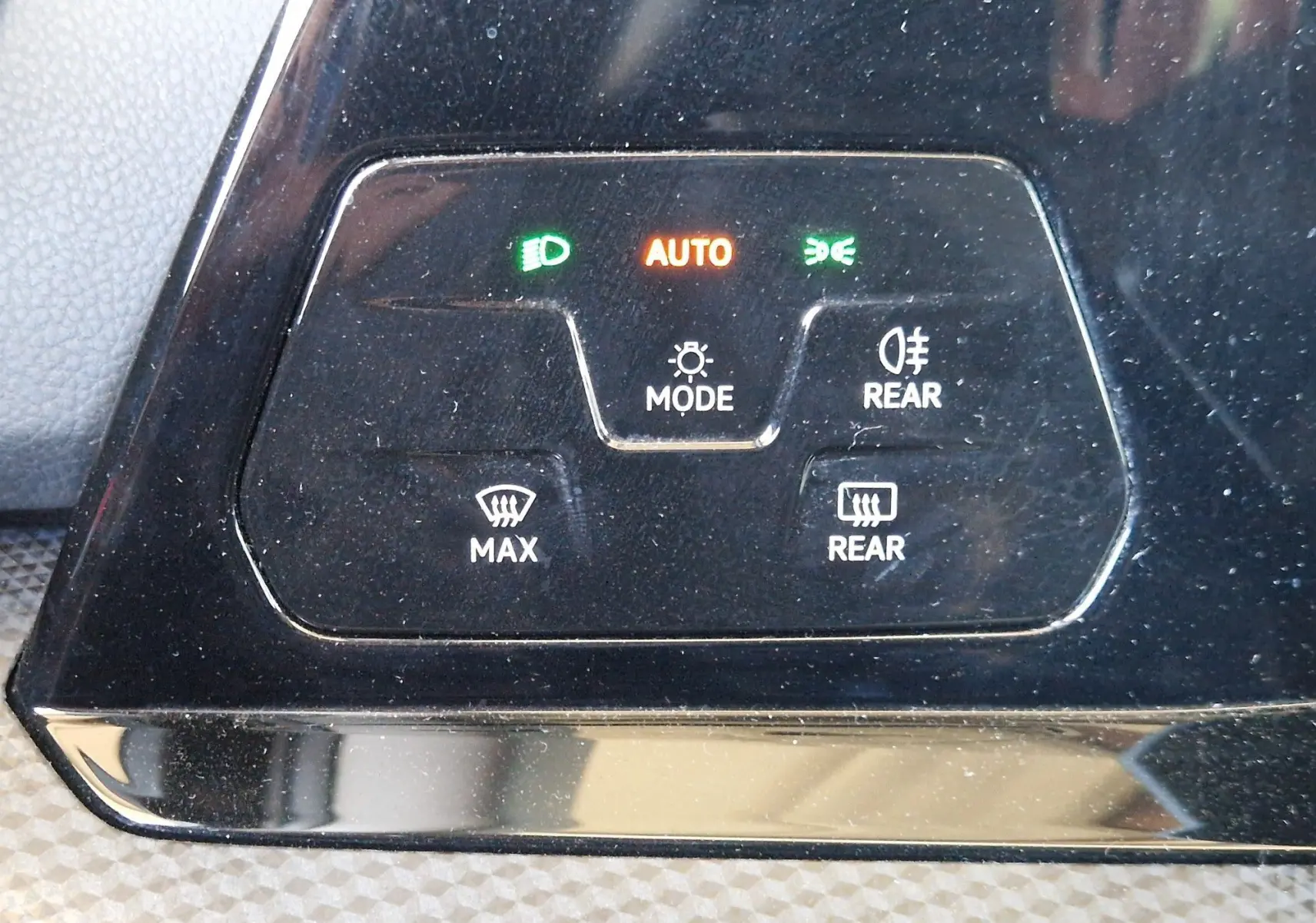 Panneau de commandes d'éclairage et désembuage de la Volkswagen Golf VIII noir métal, avec voyants verts et orange allumés.