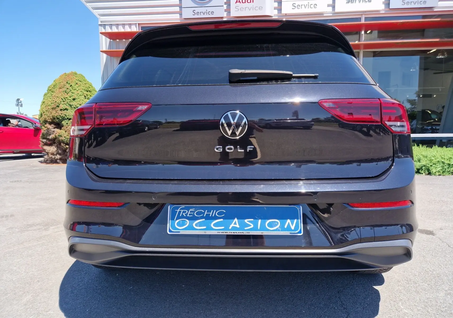 Vue arrière d'une Volkswagen Golf VIII noire métallisée avec logo VW et plaque d'occasion bleue visible.