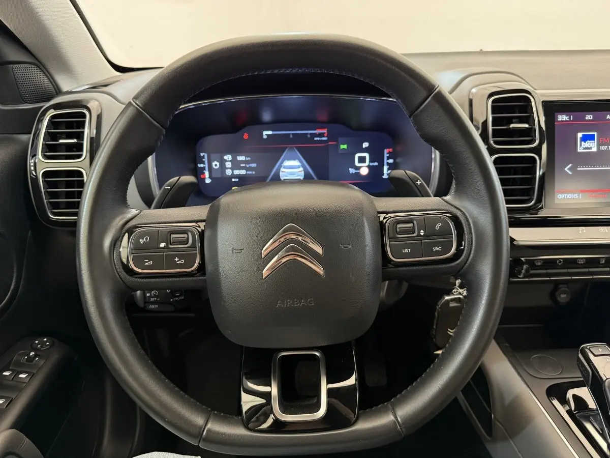 Vue rapprochée du volant cuir noir de la Citroën C5 Aircross 2020 avec tableau de bord numérique et écran tactile.
