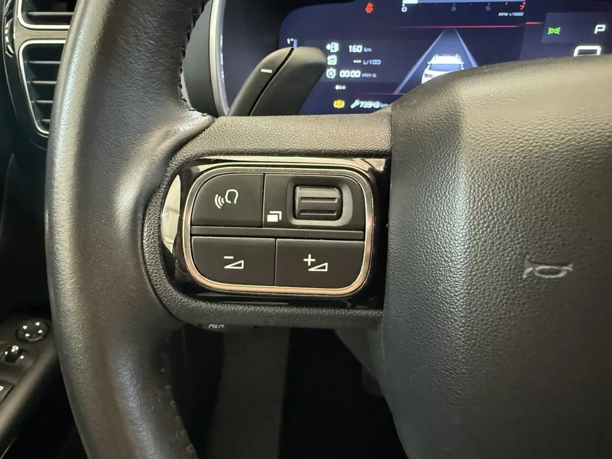 Gros plan sur les commandes gauche du volant cuir noir du Citroën C5 Aircross 2020 avec affichage numérique en arrière-plan.
