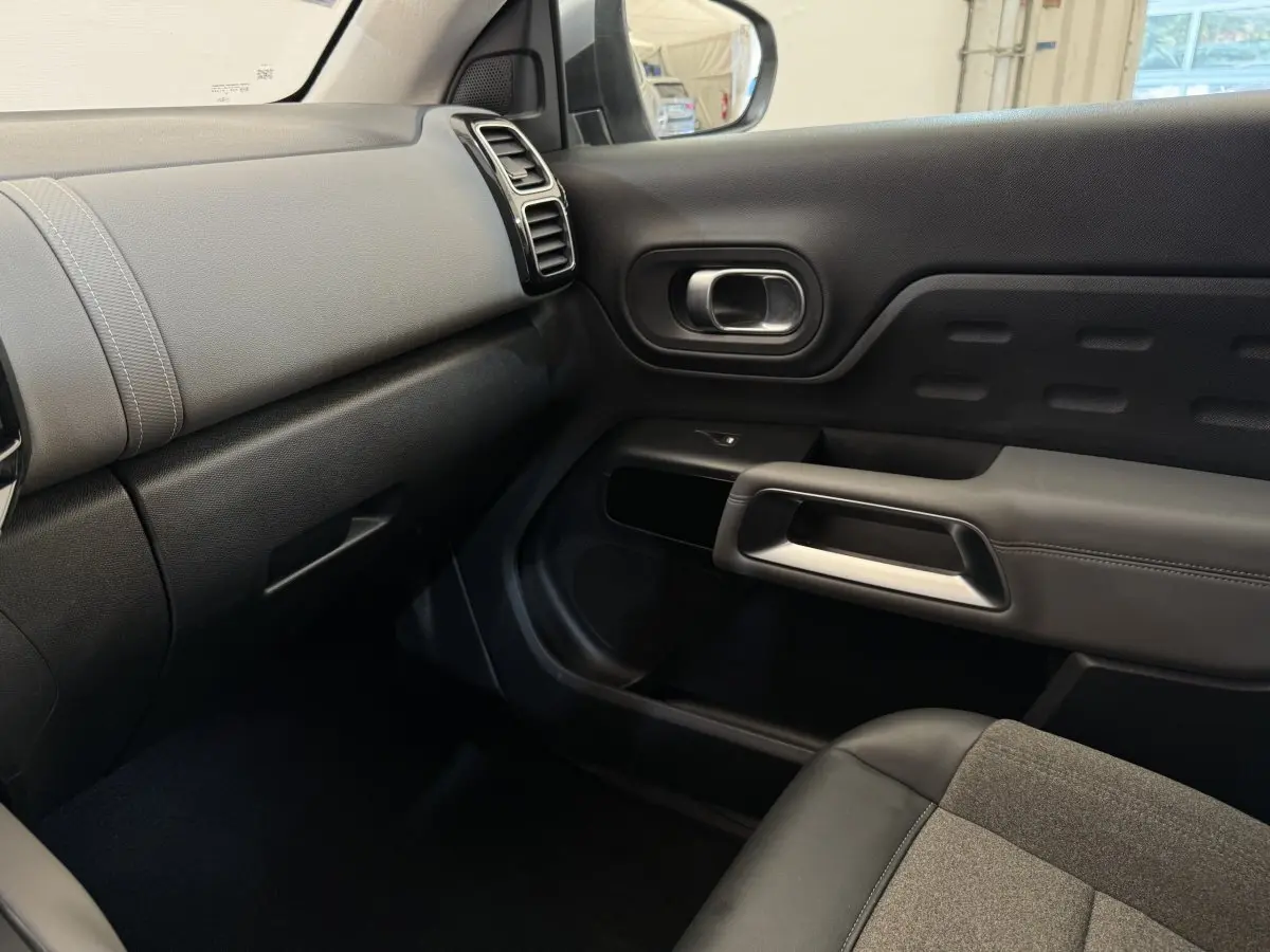 Intérieur côté passager du Citroën C5 Aircross gris clair, montrant tableau de bord et porte avec détails en tissu et cuir noir.