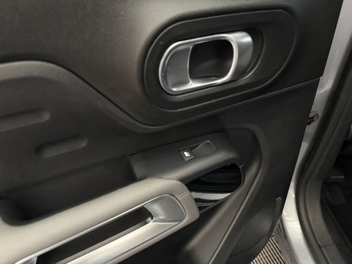 Détail de la porte avant gauche gris clair du Citroën C5 Aircross avec poignée argentée et commande de vitre électrique.