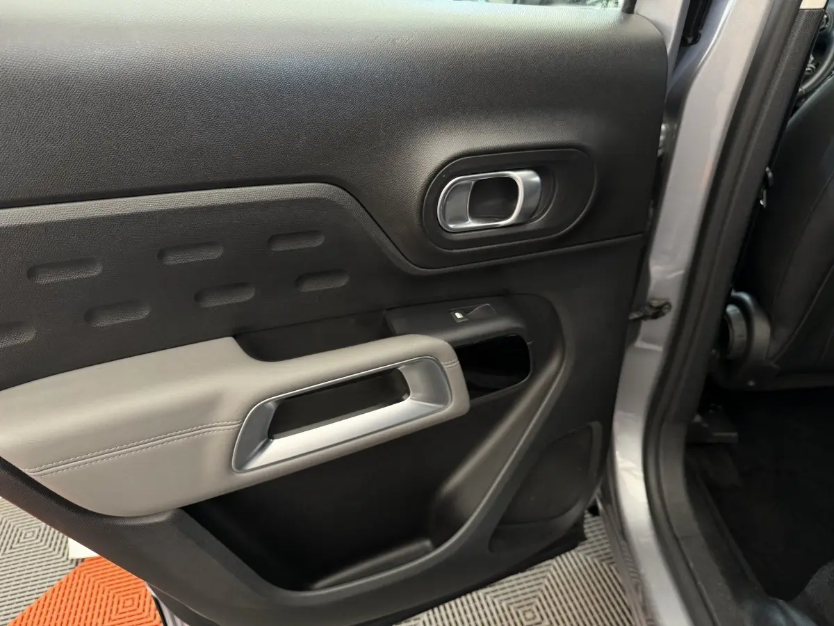 Vue intérieure côté gauche de la porte arrière grise du Citroën C5 Aircross avec poignée argentée et garniture noire et grise.