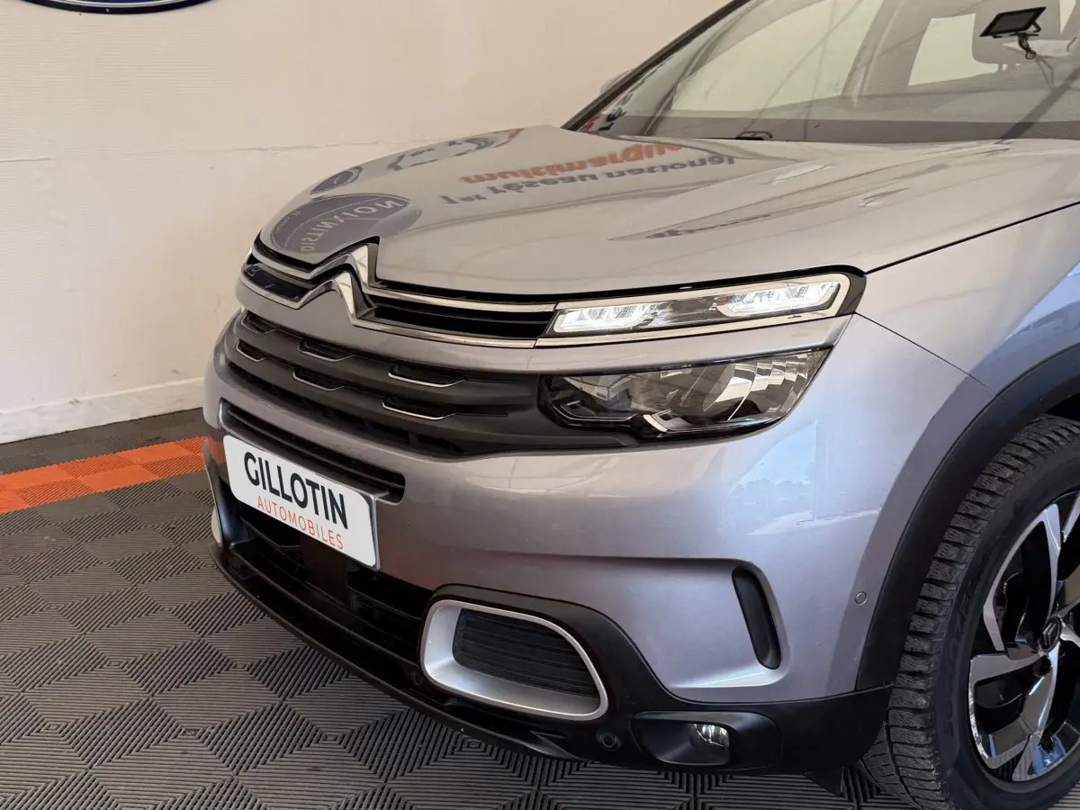 Gros plan sur l'avant droit d'une Citroën C5 Aircross gris clair avec feux LED et calandre distinctive
