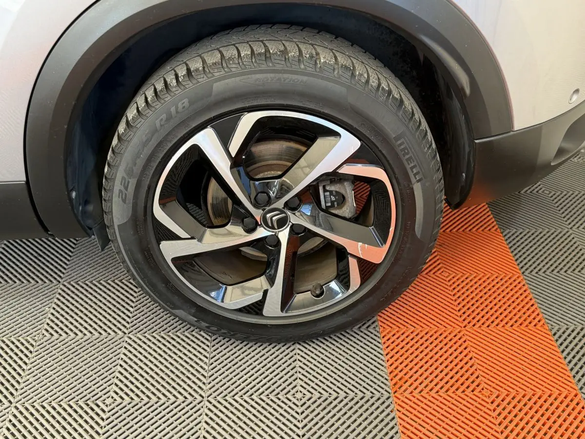 Gros plan sur la roue avant droite d'un Citroën C5 Aircross gris clair avec jante alliage noire et argentée.