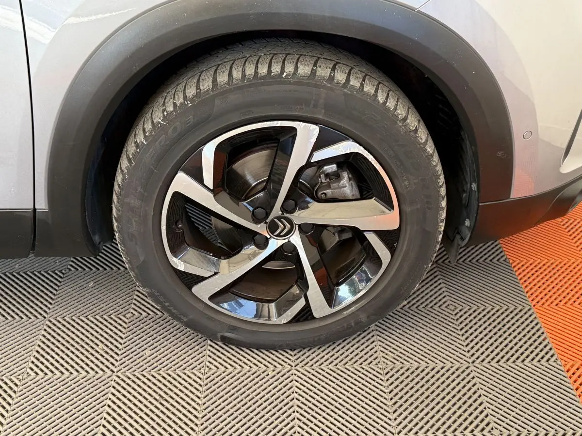 Gros plan sur la roue avant droite d’un Citroën C5 Aircross gris clair avec jante alliage bicolore moderne.