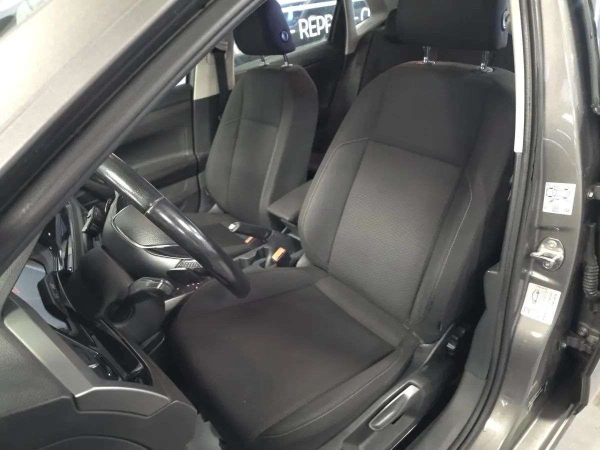 Vue intérieure côté conducteur de la Volkswagen Polo gris 2020 avec sièges tissu noirs et volant cuir multifonction.