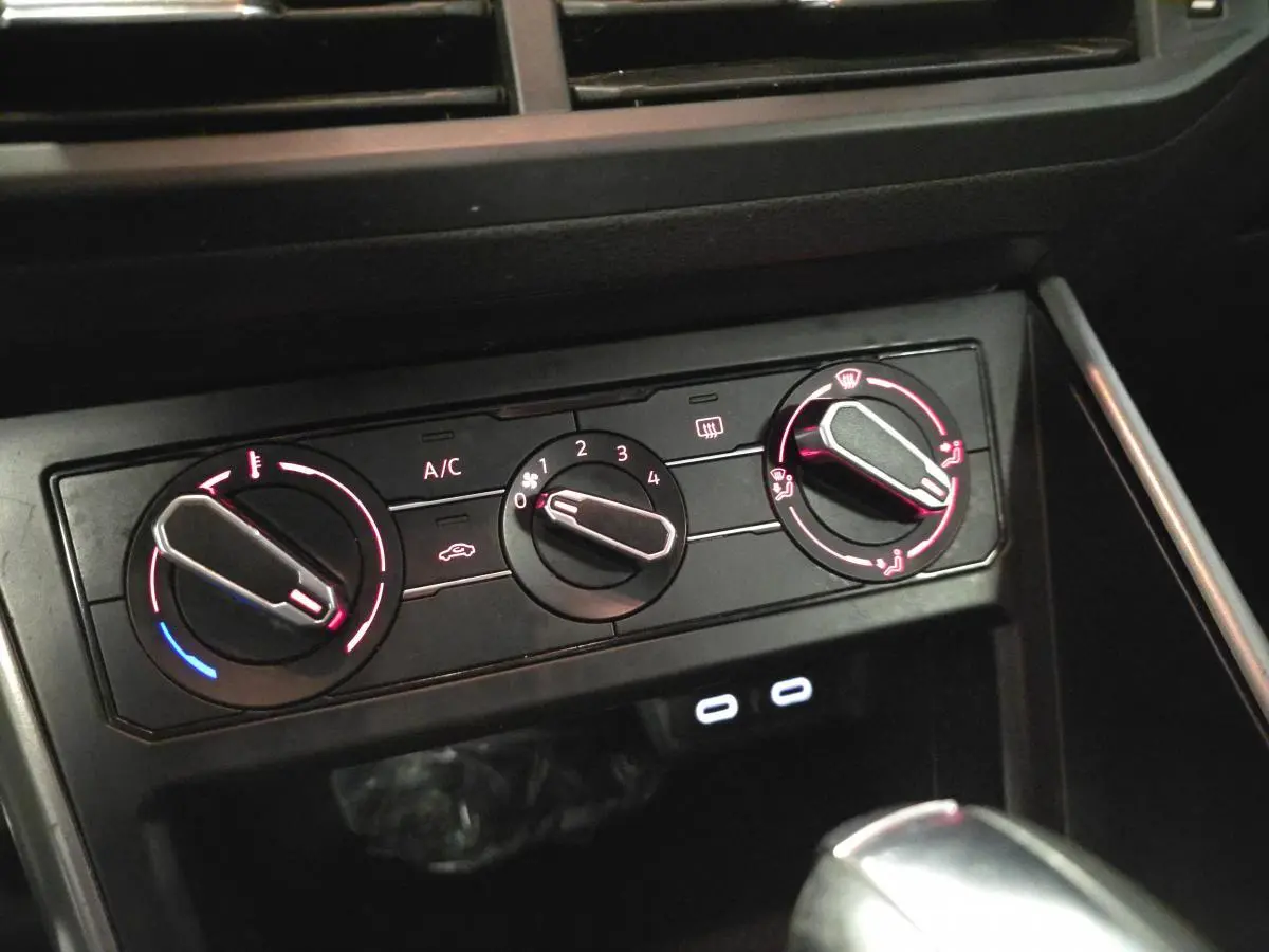 Gros plan sur la console centrale de la Volkswagen Polo 2020 avec commandes de climatisation manuelle et ports USB-C éclairés.