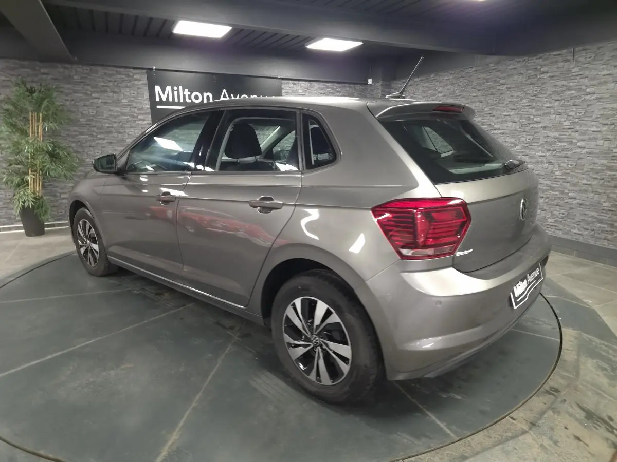 Vue 3/4 arrière droite d'une Volkswagen Polo gris métallisé avec jantes alliage et feux arrière rouges.