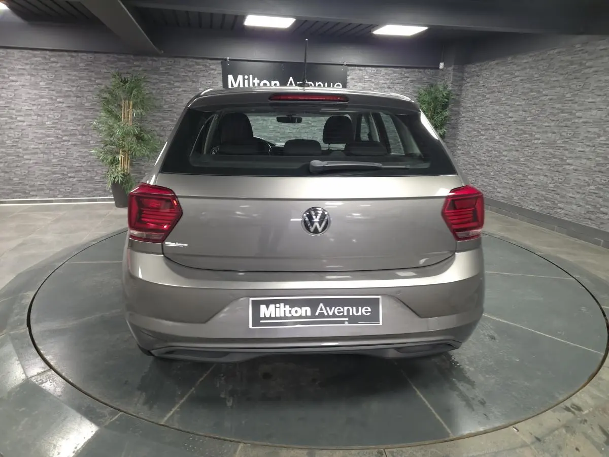 Vue arrière d'une Volkswagen Polo gris métallisé 2020 avec feux rouges et logo VW visible, stationnée en intérieur.