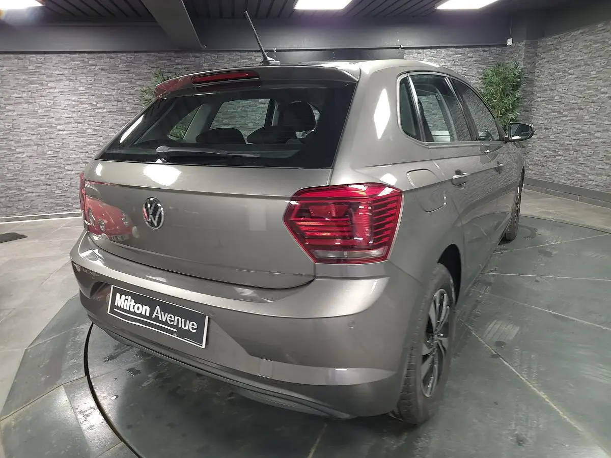 Vue 3/4 arrière droite d'une Volkswagen Polo gris métallisé avec jantes alliage et antenne de toit.