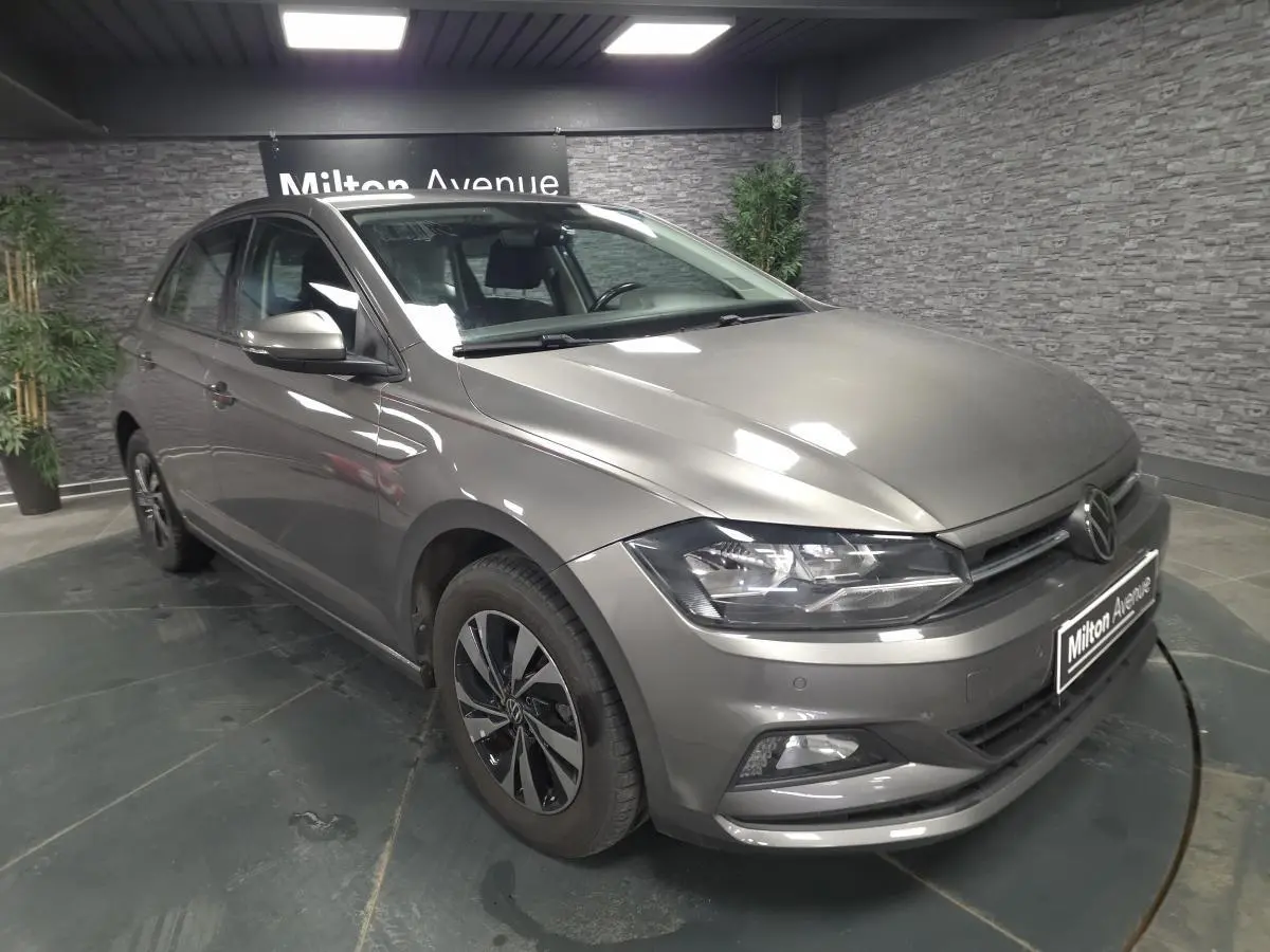 Volkswagen Polo gris 3/4 avant droit avec jantes alliage et phares LED dans showroom.